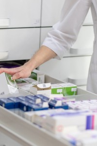 Pharmacist holding medicine box and capsule pack in pharmacy drugstore.